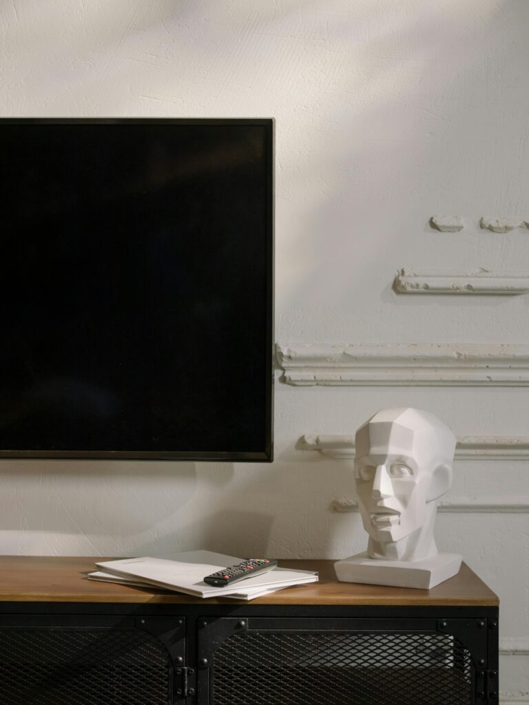 Modern interior with a TV, geometric sculpture, and wooden table decor.